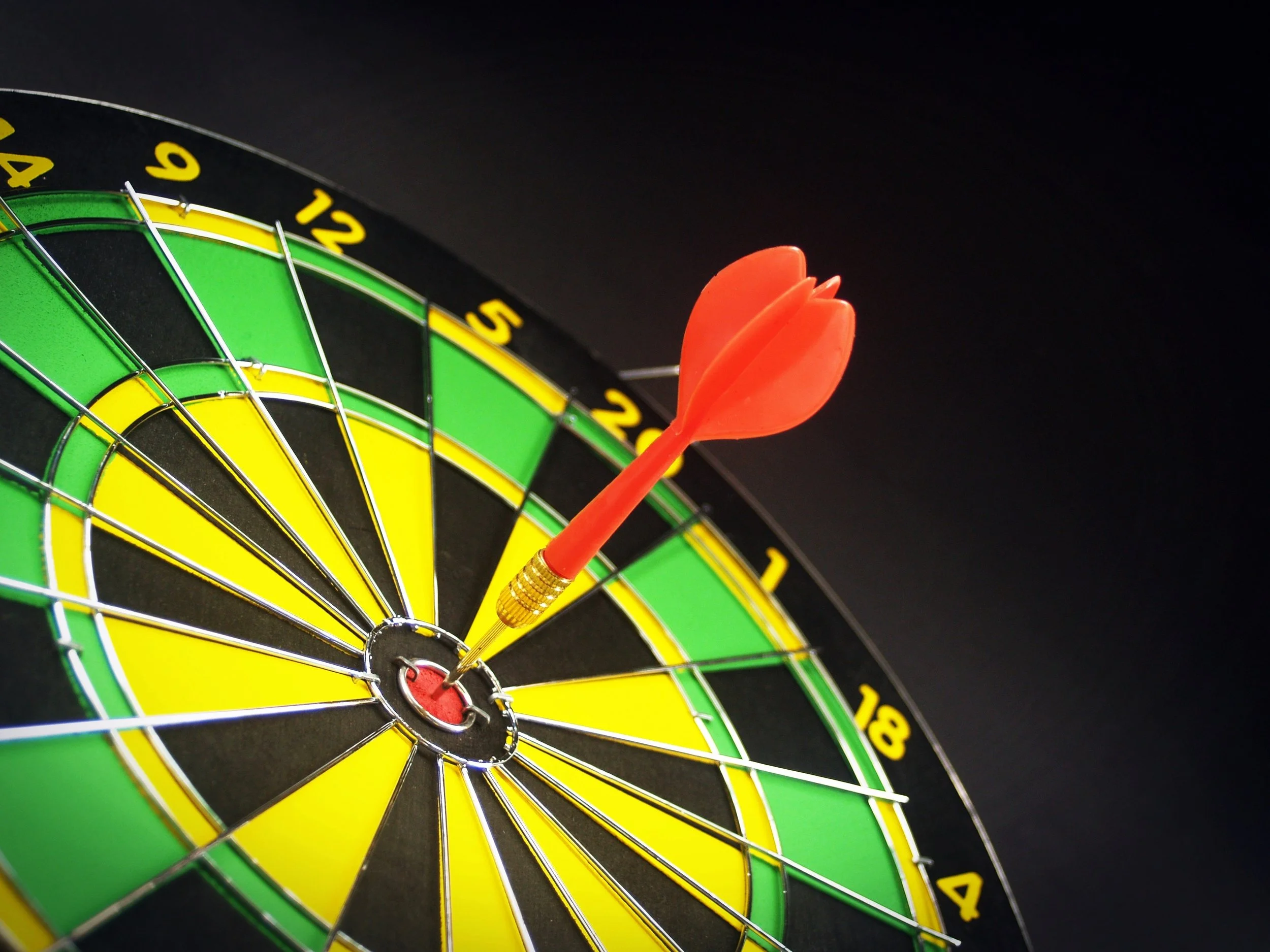 Red dart hitting the bullseye of a dartboard