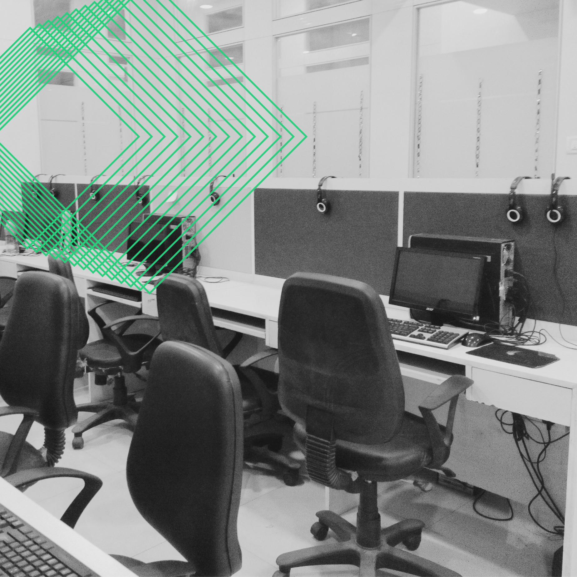 Empty open-plan office with rows of desks, computers and headsets, with a green JOT chevron graphic